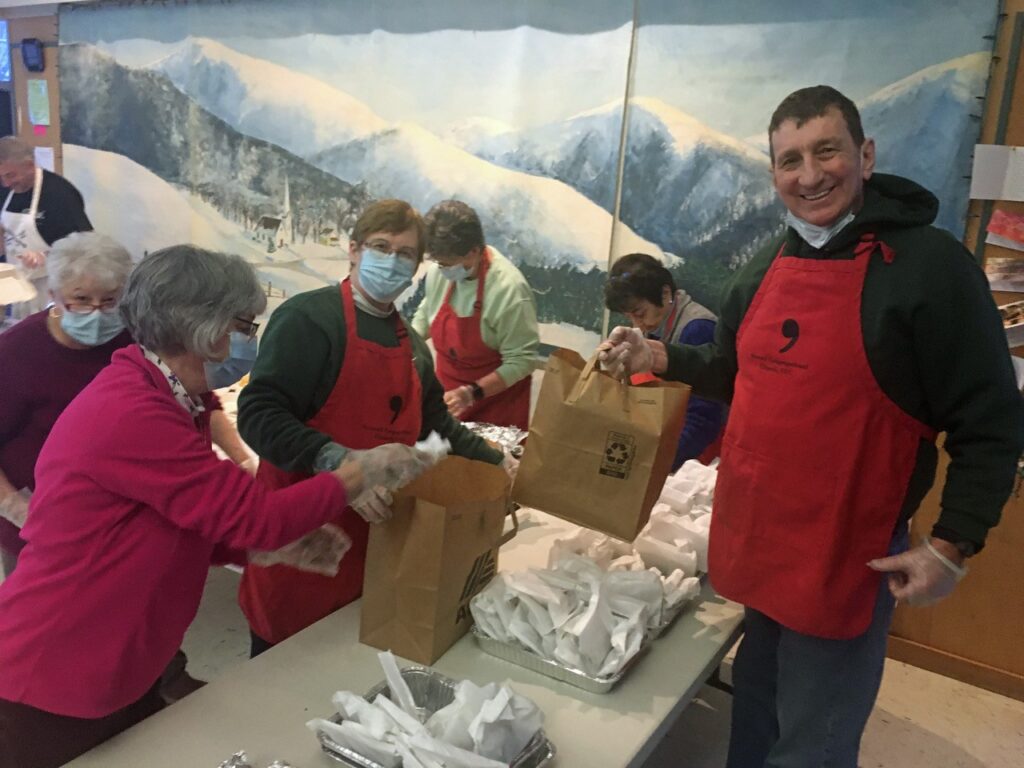 Smiling people serving community meal