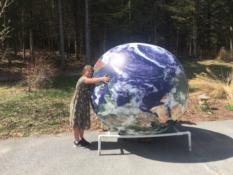 Small child hugging a giant blow up earth