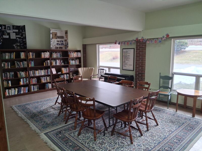room with many bookshelves, in center several tables and chairs