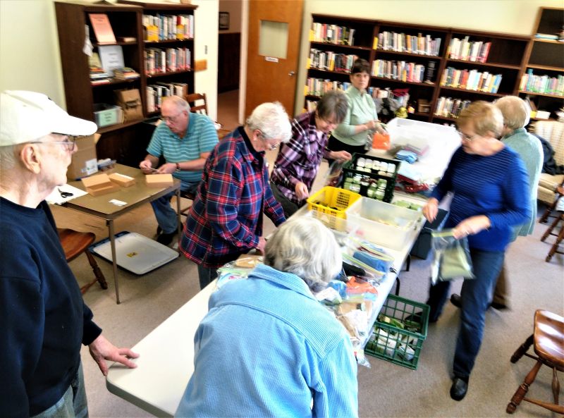 Group of people assembling kits from items on table