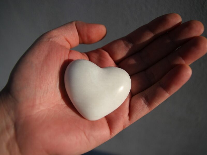 A white heart shaped stone held in an open hand