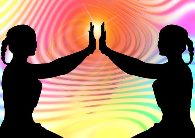 silhouette of two women with arms outstretched embracing the bright colorful sun set