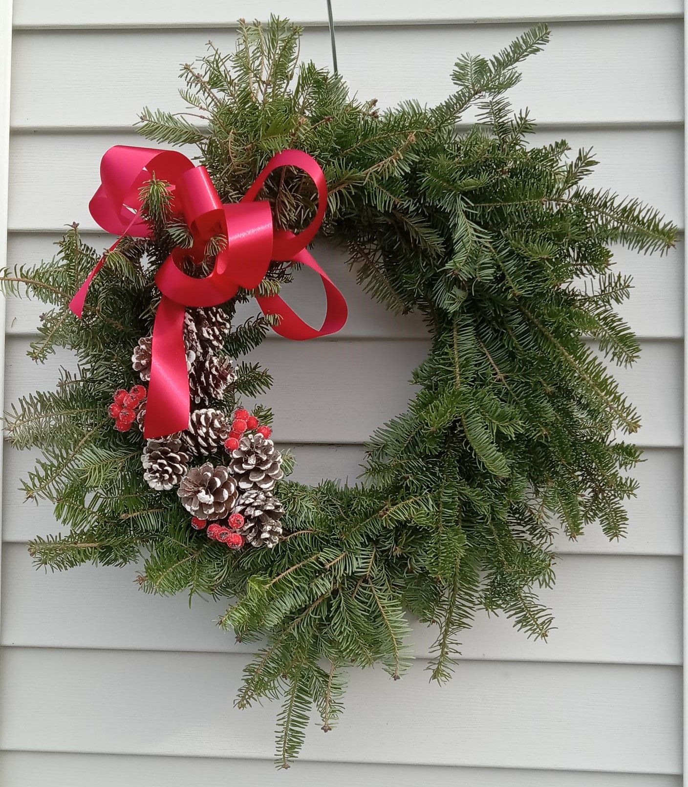 green wreath with red bow and pinecones