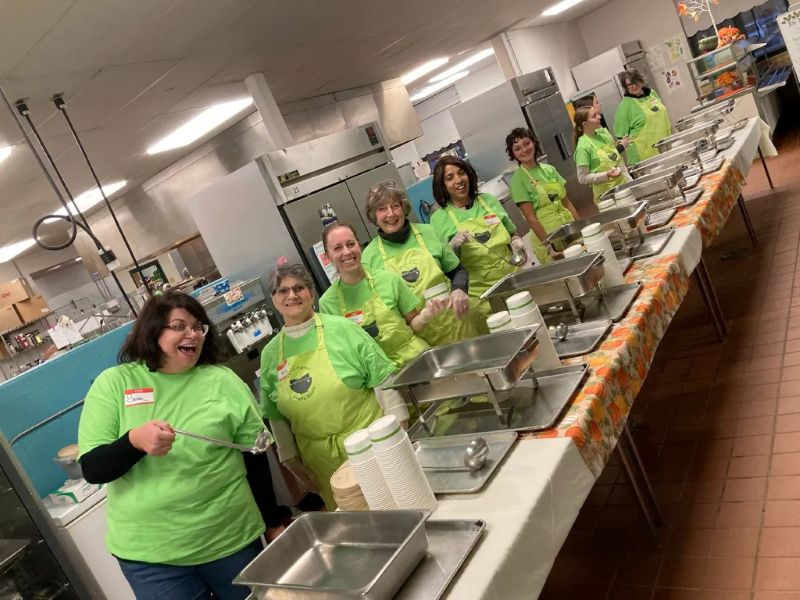 A line of smiling volunteers serving soup